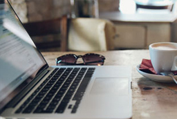 Laptop, coffee cup, and sunglasses on table