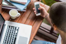 Student looking at laptop and cell phone